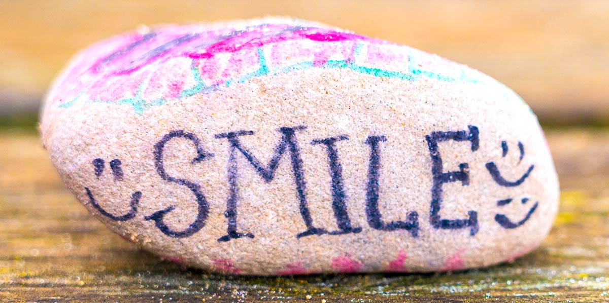 a rock with the word smile and happy faces painted on it