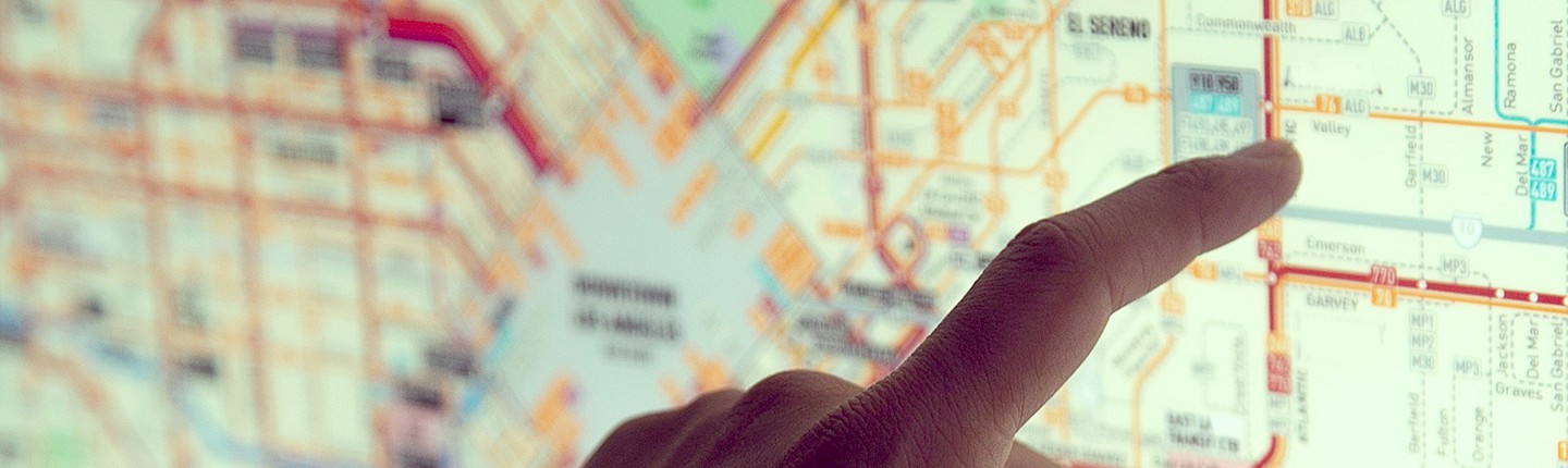 a hand with index finger pointing at a general street map